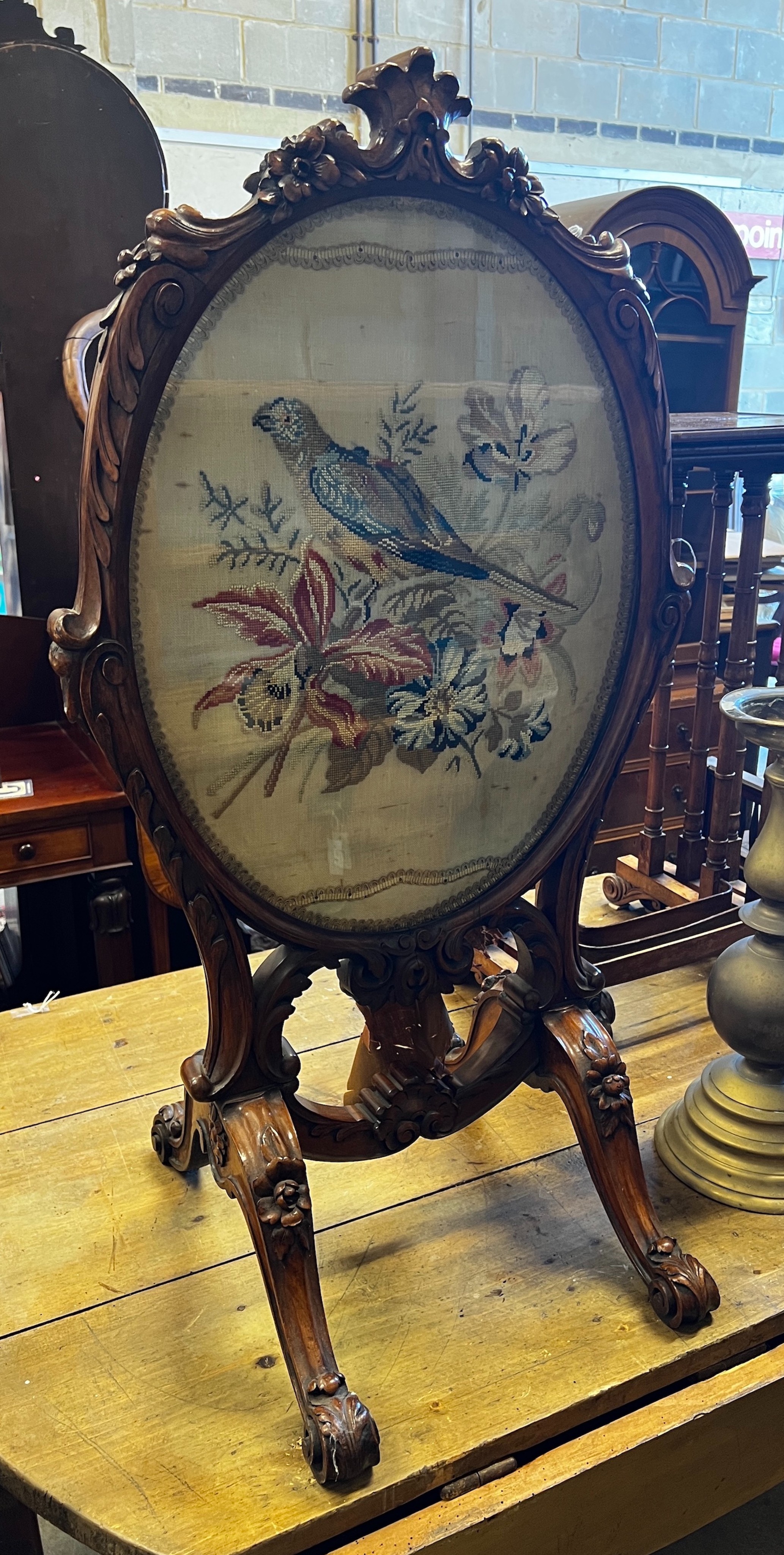 A Victorian carved walnut fire screen with needlework parrot banner, width 56cm, height 99cm